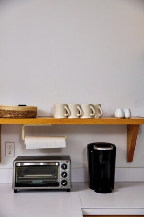 A kitchen with a wooden shelf holding mugs and a toaster oven. - Catskill Seasons Inn (Shandaken)