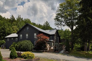 A two-story house with a porch and a staircase leading to the entrance.