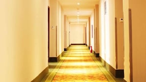 A long, narrow hotel corridor with a patterned carpet and doors on either side. - GreenTree Inn Qingdao Development District SDUST Express Hotel (Qingdao)