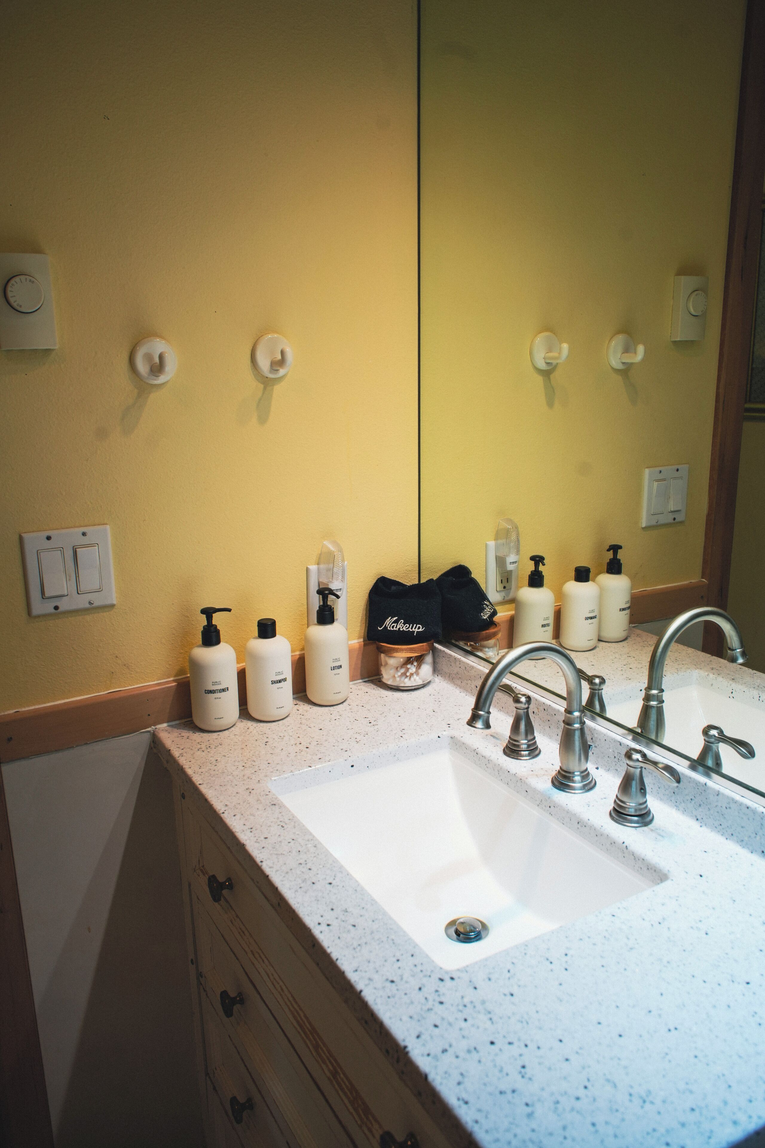 Een badkamer met een wit wastafel, verzorgingsproducten en een spiegel.