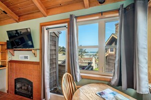 Una habitación acogedora con chimenea, televisor montado en la pared y un ventanal con cortinas.