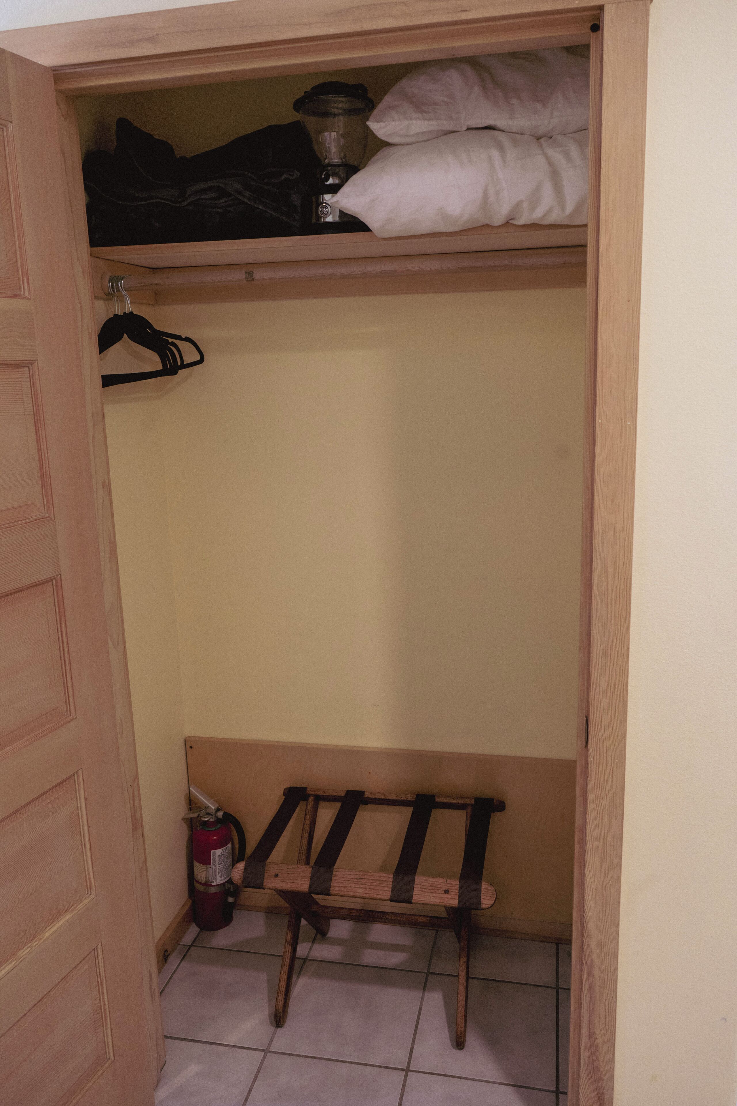 Ein Schrank mit Sitzbank, Kleiderstange und Feuerlöscher.