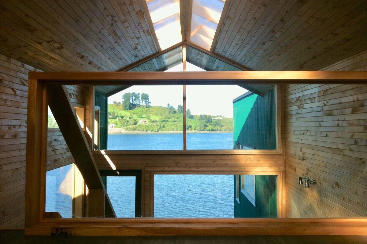 A cabin with a large skylight and a view of a lake and hills.