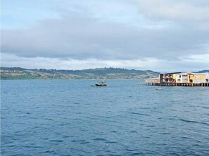 Una propiedad frente al agua con un muelle que se adentra en una masa de agua tranquila, rodeada de colinas.