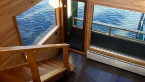 A wooden interior with a view of the sea through large windows. - Palafito Verde Apart Hotel (Castro)