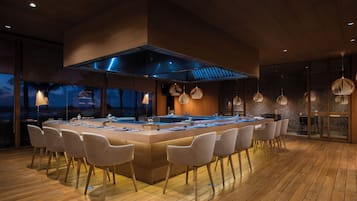 A modern kitchen with a central island, seating area, and large windows overlooking a scenic view.