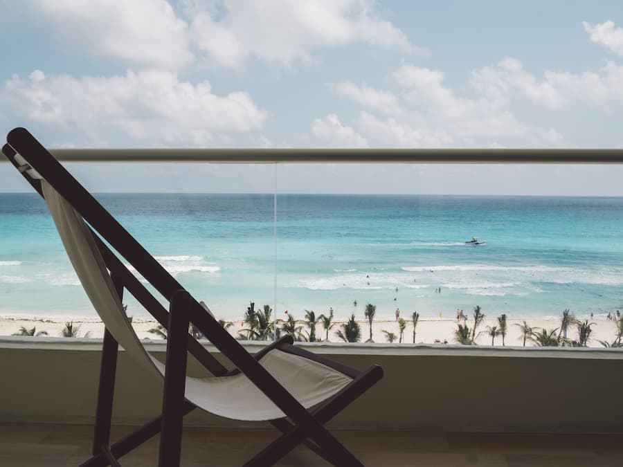 Vista al mar desde un balcón con una silla de madera.