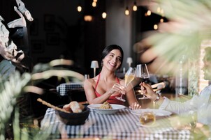Un tavolo da pranzo con piatti di cibo, bicchieri e una persona che brinda.
