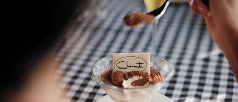 A dessert in a glass bowl with a label, placed on a checkered tablecloth.