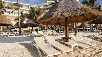 En la playa, playa de arena blanca y camas de playa (con cargo)