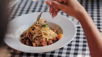 Un plato de espagueti con carne y verduras sobre un mantel a cuadros.
