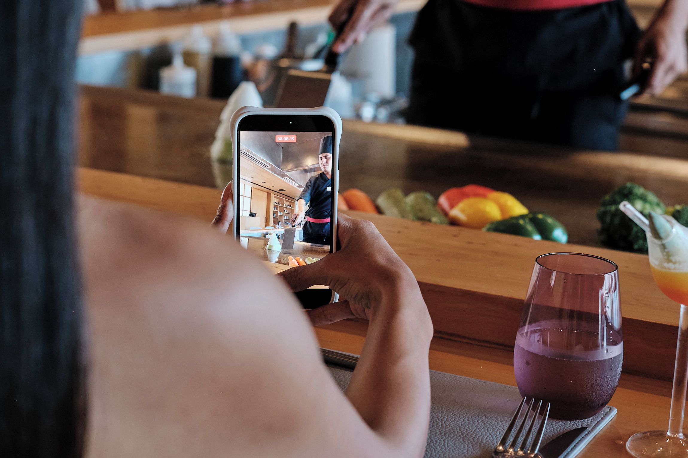A person taking a photo with a smartphone at a restaurant.