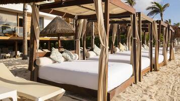 En la playa, playa de arena blanca y camas de playa (con cargo)
