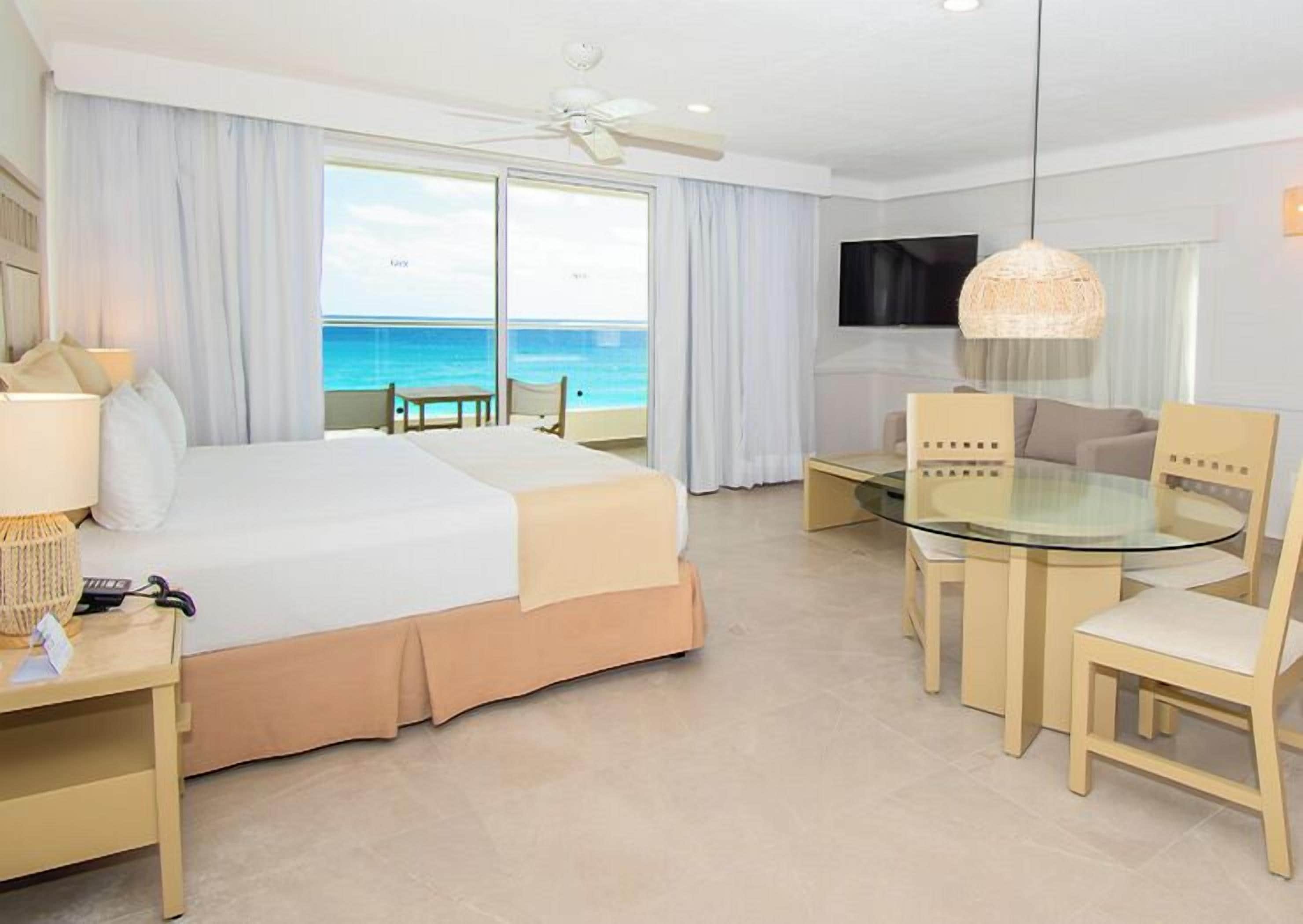 Una habitación de hotel con una cama grande, una mesita de cristal y vistas al océano.