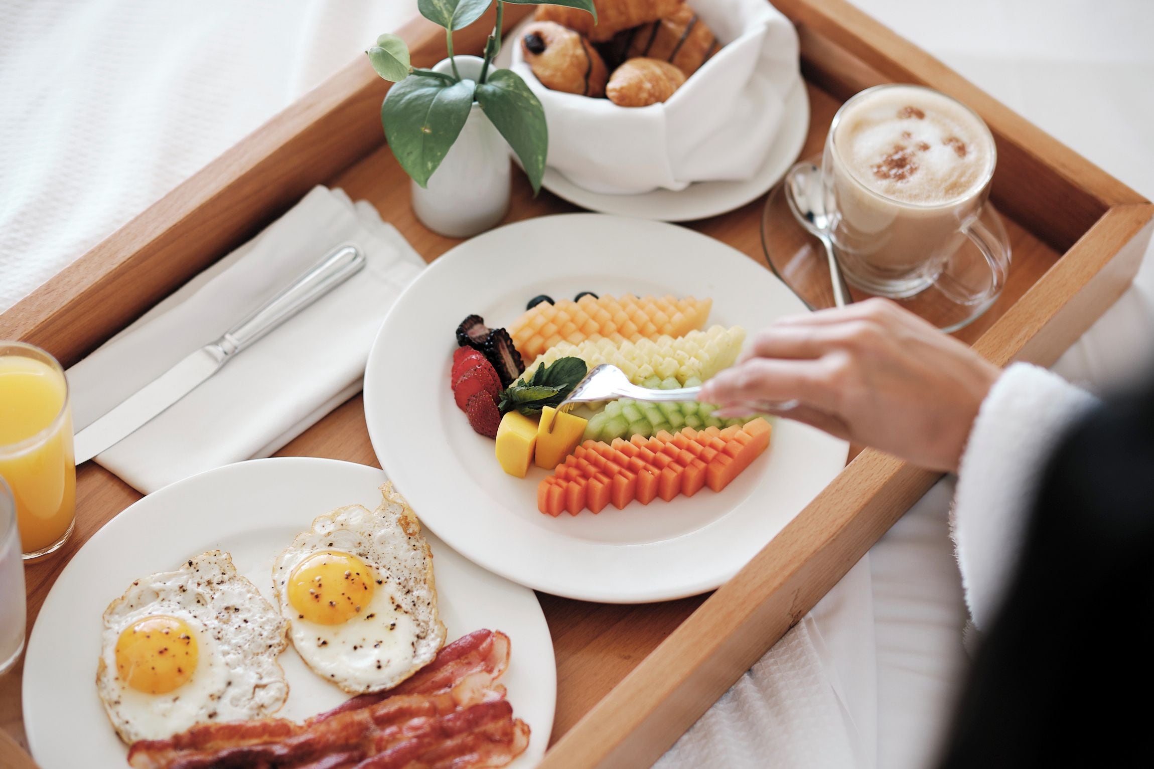 Bandeja de desayuno con huevos, tocino y diversas frutas y verduras.