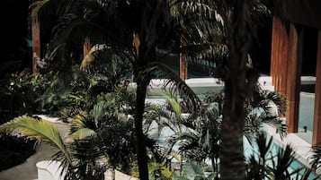 Zona de piscina con palmeras y un edificio al fondo.