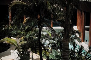 Zona de piscina con palmeras y un edificio al fondo.