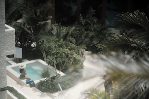 A pool area with a hot tub, surrounded by dense tropical foliage.