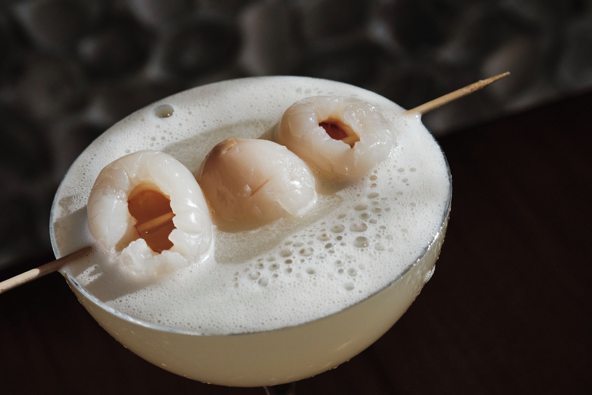 Een cocktail met drie bolvormige versieringen op een schuimend oppervlak.
