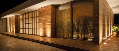 A modern building with large glass windows, wooden paneling, and a paved walkway.