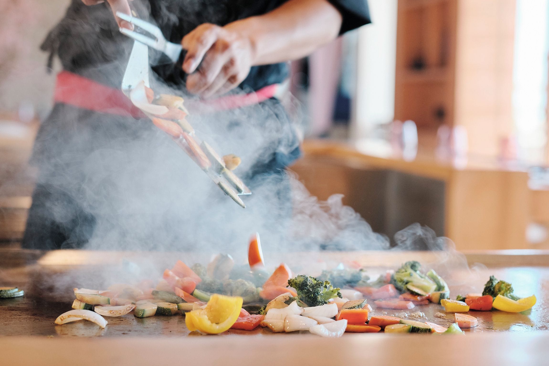A person grilling vegetables on a flat surface.