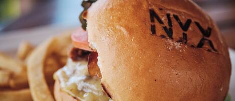 A sandwich with a bun, cheese, and meat, accompanied by fries.