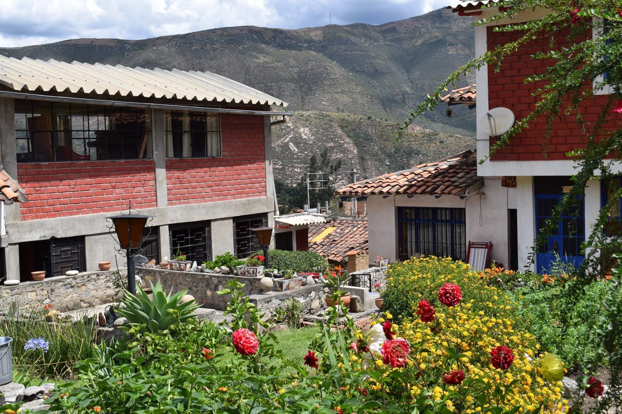 Um edifício tradicional com telhado de azulejos, rodeado por um jardim com diversas plantas e flores.
