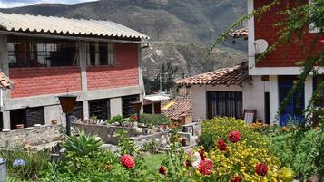 Um edifício tradicional com telhado de azulejos, rodeado por um jardim com diversas plantas e flores.