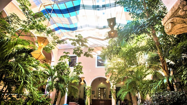 An indoor atrium with a high ceiling, arches, and lush greenery. - Hotel Merida (Mérida)