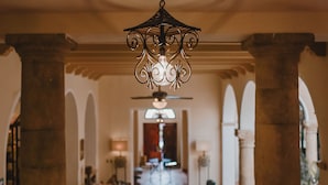 A grand hallway with a red patterned carpet, ornate ceiling, and classical columns. - Hotel Merida (Mérida)