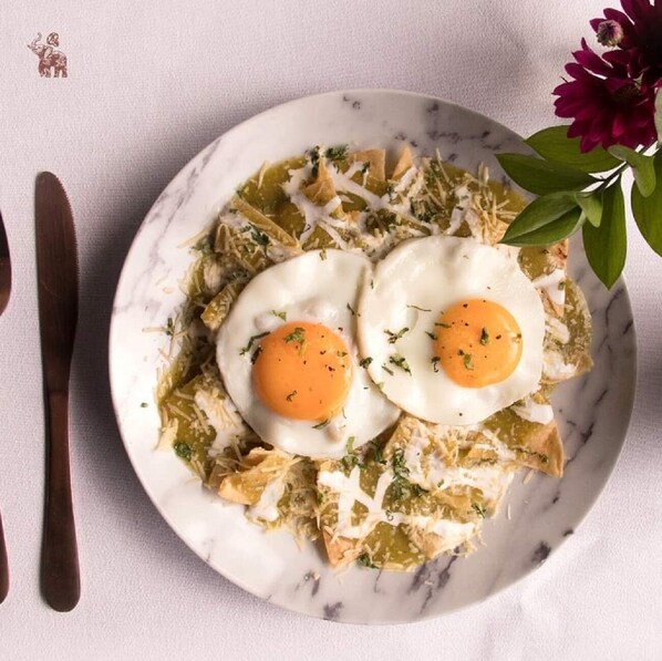 Un plato de nachos con dos huevos fritos encima, adornado con hierbas.
