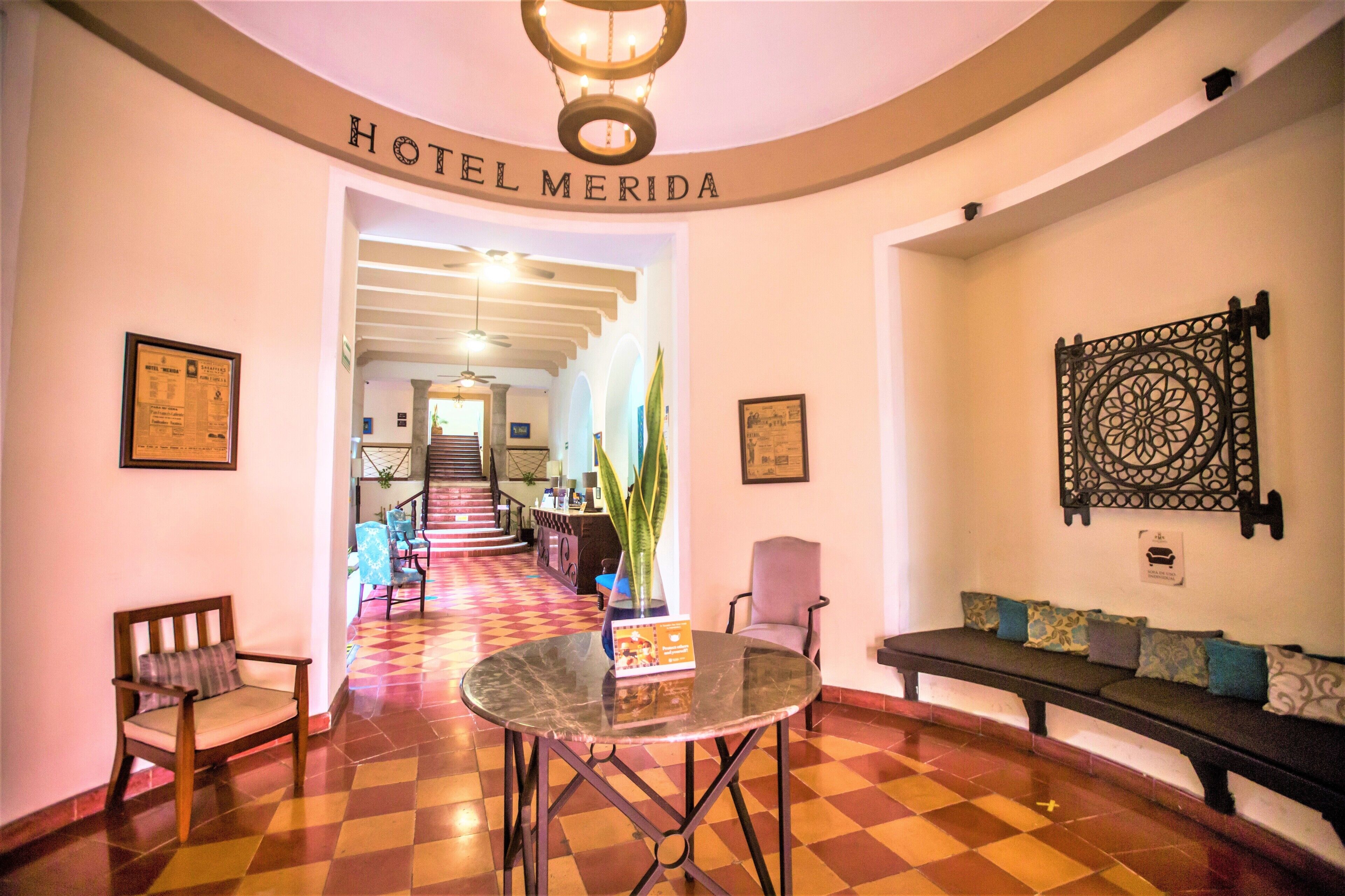 Eine Hotelhalle mit Schachbrettmuster-Boden, einer Rezeption, einer Sitzecke mit Sofa und Sesseln sowie einem Chandelier.
