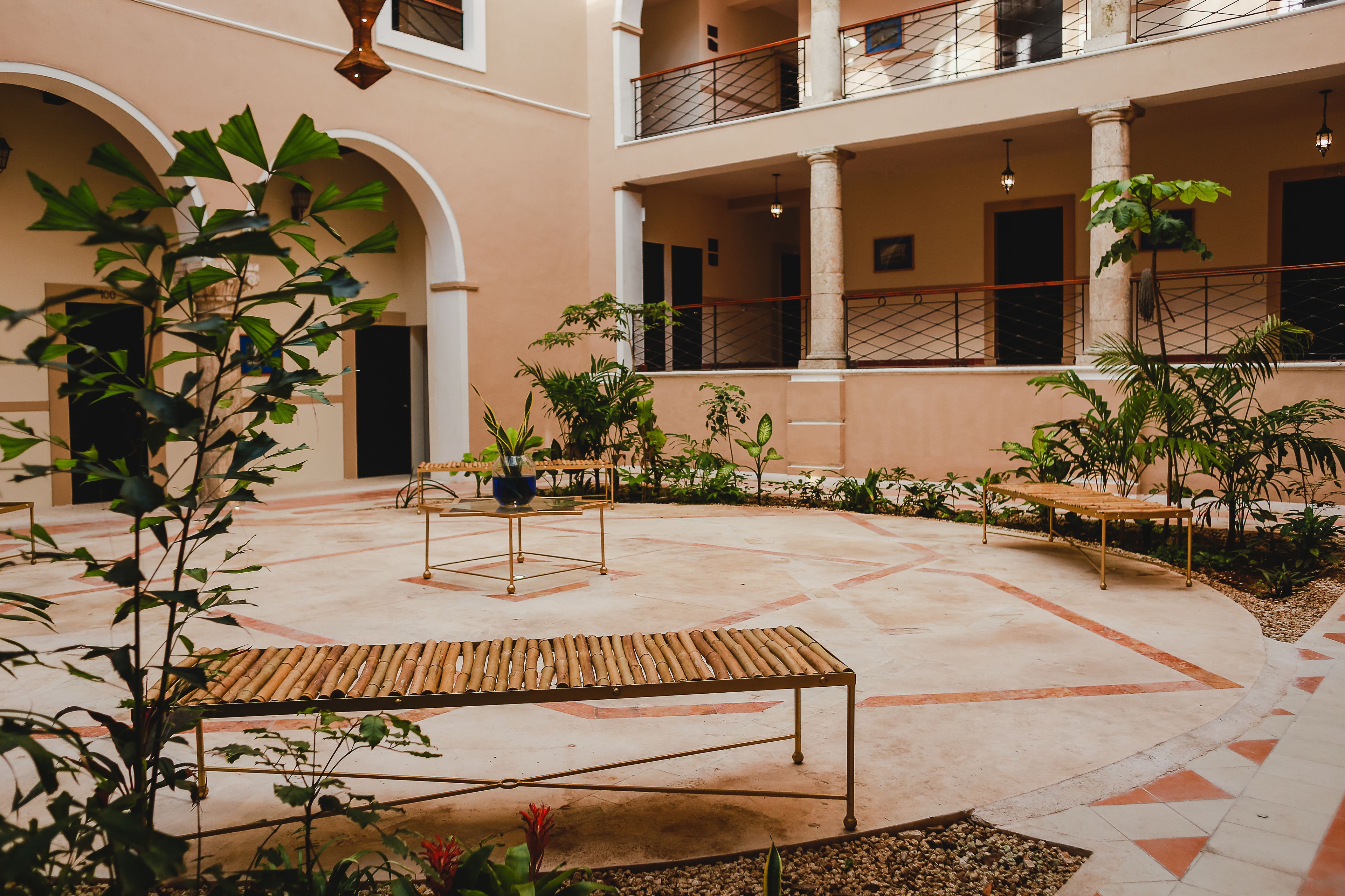 A spacious courtyard with a central seating area, surrounded by plants and columns.