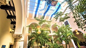 A spacious atrium with high ceilings, large windows, and multiple palm trees. - Hotel Merida (Mérida)
