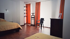 A bedroom with a bed, a chair, a wardrobe, and a shelf unit. - Hotel Avanty (Ipiales)