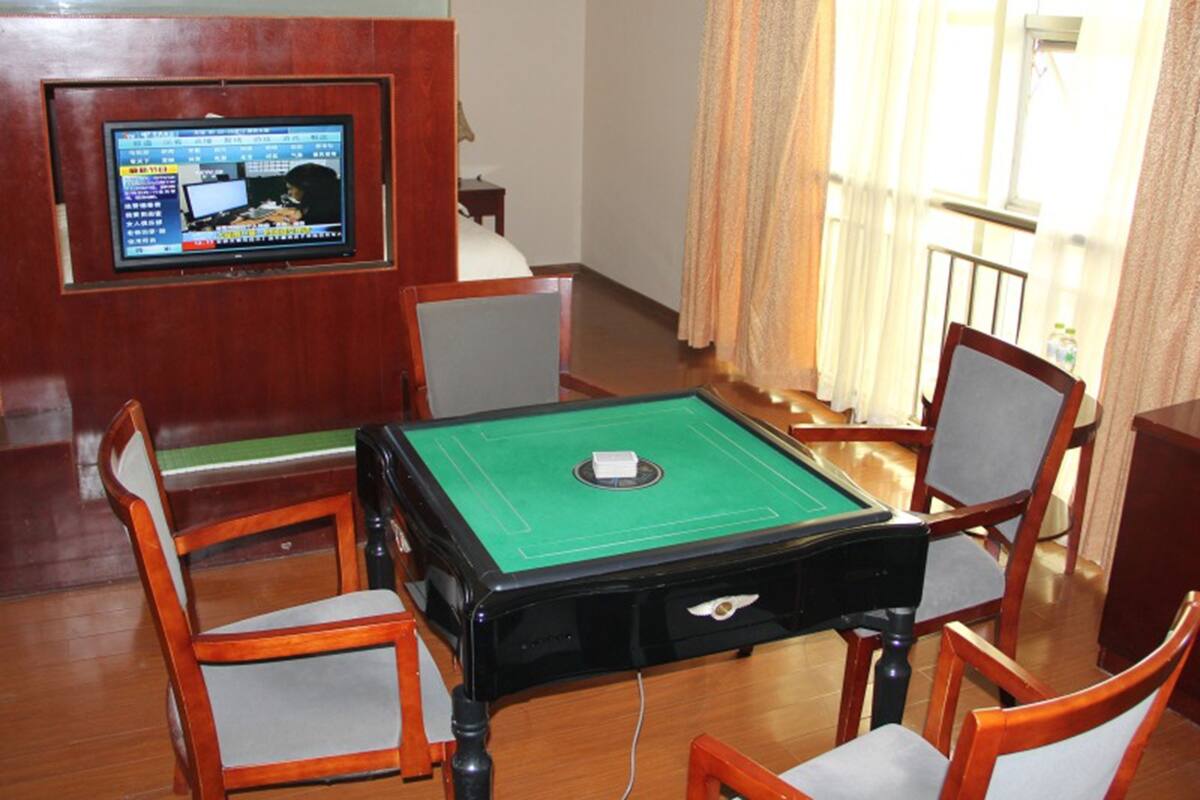 Una habitació amb billar, cadires de fusta, televisió penjada a la paret i una finestra amb cortines.
