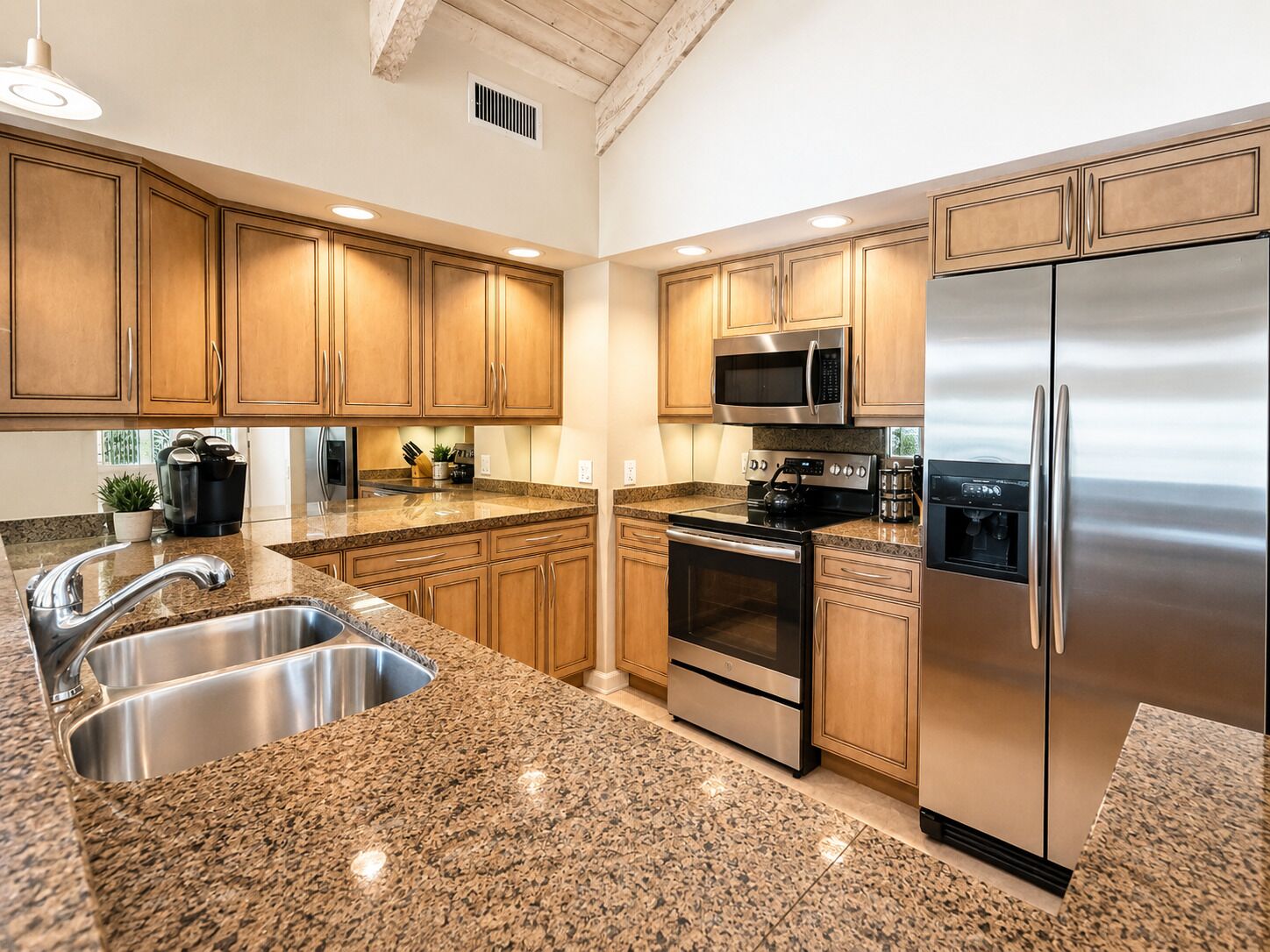 A kitchen with granite countertops, stainless steel appliances, wooden cabinets, and a built-in oven.