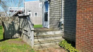 A residential property with a wooden deck, a brick exterior wall, and a front door. - Great Vacation Place Just Steps From The Beach (Falmouth)