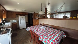 A kitchen with wooden cabinets, a refrigerator, a microwave, and a dining table with chairs. - Great Vacation Place Just Steps From The Beach (Falmouth)