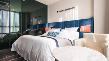 Una habitación de hotel con una cama grande, una mesa redonda y una silla. Se observa una pared con un cartel que dice "Best Louis Hamilton Hotel".