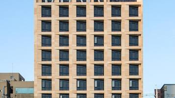 Un moderno edificio de hotel con un llamativo letrero 'KY' en la fachada, varios pisos y una vista despejada de la calle.