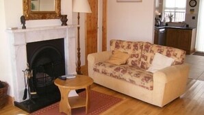 Un soggiorno con camino, un divano, un piccolo tavolino in legno e un cuscino decorativo.