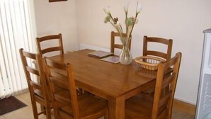 Un tavolo da pranzo in legno con quattro sedie, un vaso con fiori, un cesto e un quadro appeso al muro.
