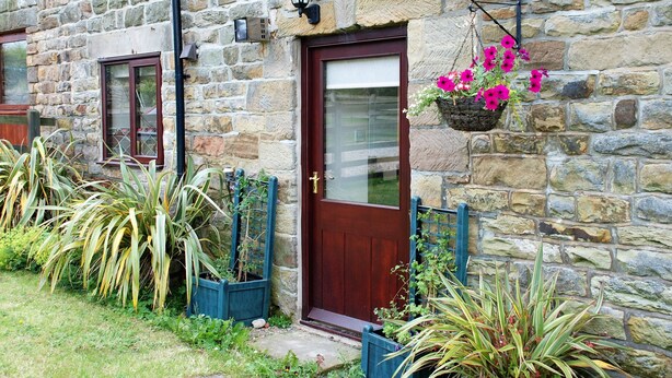 A stone building with a wooden door, a window, and a hanging flower basket.