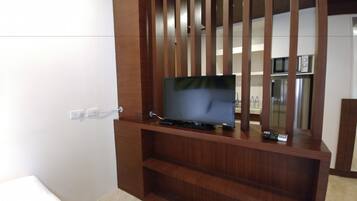 A wooden entertainment unit with a flat-screen TV, a remote control, and a power outlet.
