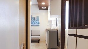 A modern hallway with a kitchen area, including a refrigerator and cabinets. - Bed and Bath Serviced Suites (Iloilo)