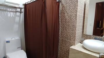 A bathroom with a shower curtain, toilet, sink, and tiled walls.