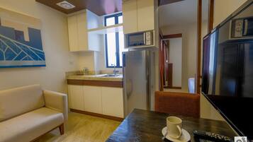 Un espacio habitable compacto con kitchenette, un sofá, una mesa de comedor y un televisor.