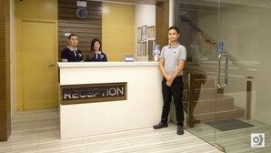 A reception desk with a sign labeled "RECEPTION," a clock, and a push button for the elevator. - Bed and Bath Serviced Suites (Iloilo)