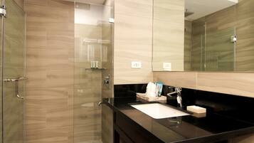 Un baño moderno con cabina de ducha de vidrio, encimera negra y un espejo grande.
